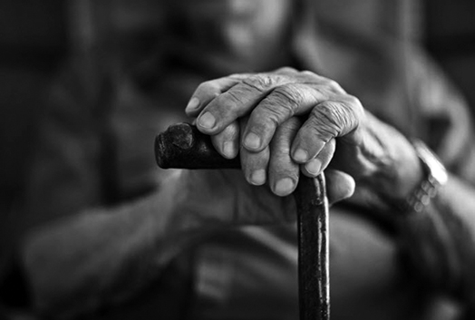 Hands of an older man resting on a cane